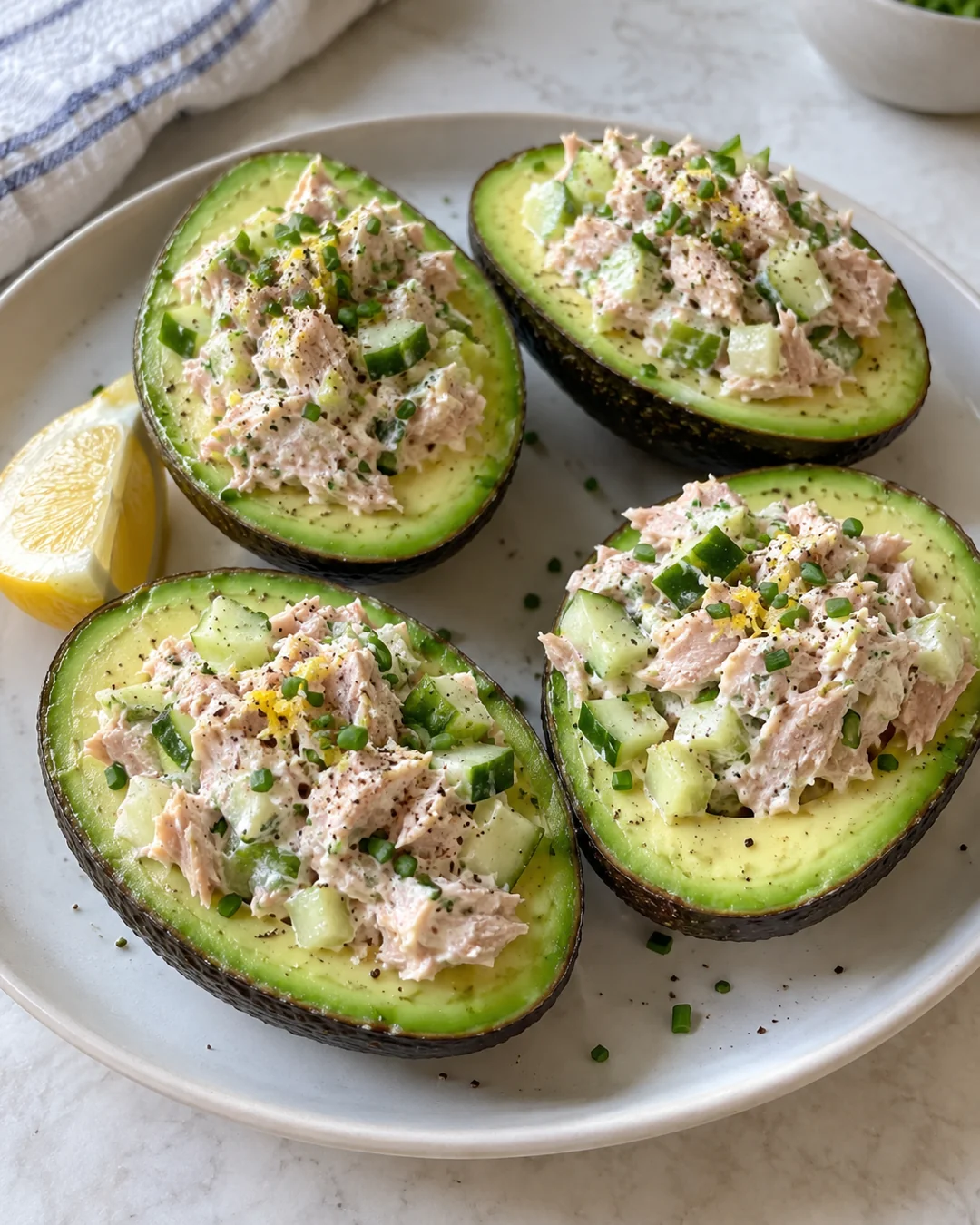 Four avocado halves filled with tuna, Greek yogurt, diced vegetables and chives.